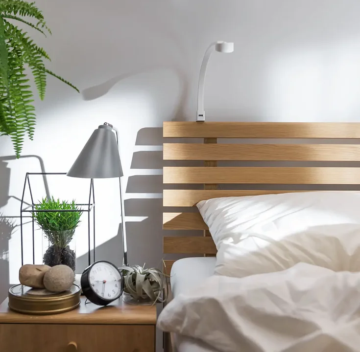 Minimalistyczna lampka nocna na drewnianym stoliku przy łóżku